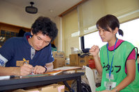 写真左が津高。先行して駐在していたJVC宮田（右）から仕事を説明してもらう。