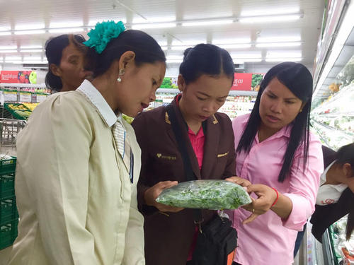 大型スーパーに並ぶ野菜を熱心に視察する農家