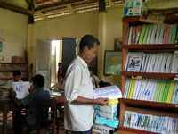 JVCが地方の図書室に支援した書籍を読む農民