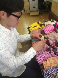 南アフリカの民族人形に商品タグをつけるインターンの舞木くん