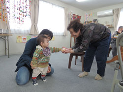 避難先から仮設を訪れている孫にお菓子を渡す仮設住民。高齢者の多くが市内の仮設に残り、避難している家族と離れ離れに暮らしている