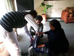 イサヌラさん（左）もいっしょに膨大な領収書を三人がかりでカバンに押し込んでいる場面。