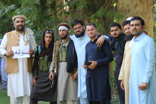 武器を持つタリバン兵士とともに。現地スタッフサビルラ（左端）の手には「平和」の文字