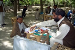 出張診療所で医薬品を患者にわたしている。後ろのテーブルは診療中。