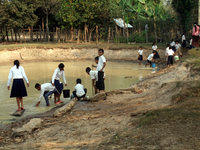 ため池の水をバケツですくう子どもたち。