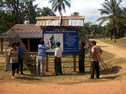 完成したPLUP掲示板を指して話し合うスタッフと村人