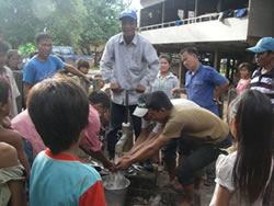 修理された井戸の水に手を伸ばす村人