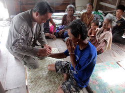 バーシーの儀式として、白糸をカンスアンさんの手首に巻いている様子。