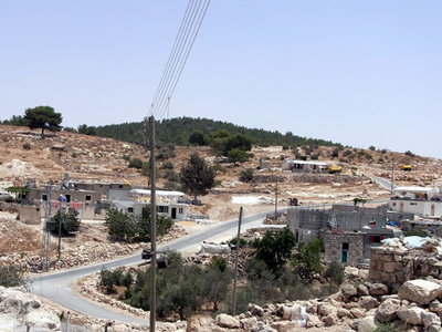 強制移住の危機に晒されている西岸地区南部のパレスチナ人集落（手前）と、緑の生い茂ったイスラエル入植地（奥）。（ヘブロン南部アル・トゥールにて）
