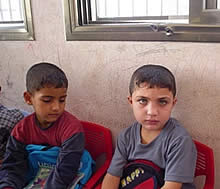 写真3:子どもたちの表情は暗かった。子どもの頭の上の窓枠の銃弾の跡は、写真2で責任者が被害を確認している場所。（2004年10月27日）