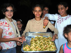 ナッツとクリームをパンケーキで挟んだ、ラマダンの特別なお菓子を配る女の子たち