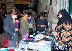 販売の様子。女性グループのメンバー（右）も伝統のドレスで参加