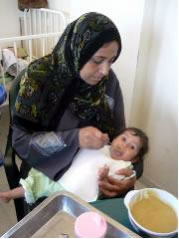 栄養失調の度合いが「5」のダリアちゃんに栄養食を食べさせるお母さん