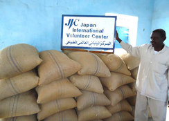 ソルガム50㎏袋。右はJVC緊急支援スタッフのユヌス・ハルーン