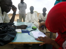 受け取り時には拇印を押してチェック。後ろで見守るのは地区住民のリーダー