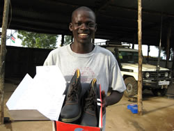安全靴を手にして笑顔の整備士ボスコ・ヤカニ