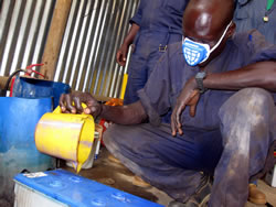 マスクを付けてバッテリー液の配合を行う研修生イペ・モーゼス