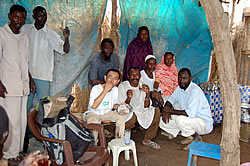 アシーダを口にする今井にはしゃぐ村人。