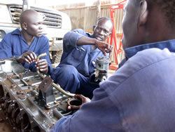 ピストンを手に研修生に説明する指導員アニャマ