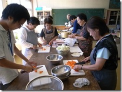 調理する住民の方々とJVCボランティアの森野さん(左側)