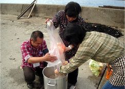 住民の方と一緒に芋煮作りに励むJVC山崎（写真左）