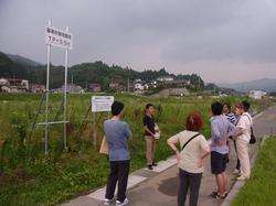嵩上げの高さを示す表示板を見上げる参加者