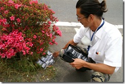 市役所わきの道路の花壇で放射線量を測る三浦万尚さん