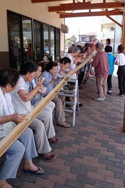 竹筒をつないで長さ6メートルにもなる滑り台。 流れてくるそうめんを上手にキャッチ