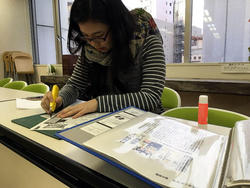 活動紹介された新聞記事をカッターで切り抜く作業
